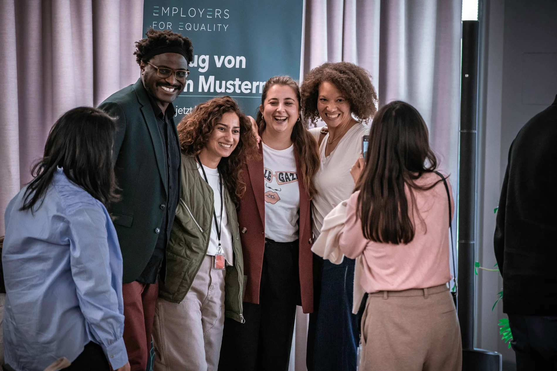 Eine Gruppe von Teilnehmenden posiert lachend für ein Foto vor der Employers-for-Equality-Wand.